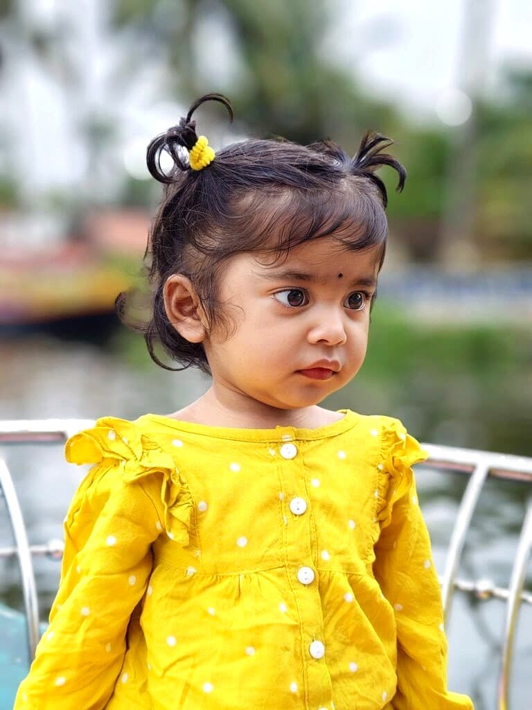 Toddler on the wooden boat deck curiously gazing across the calm village canal waters