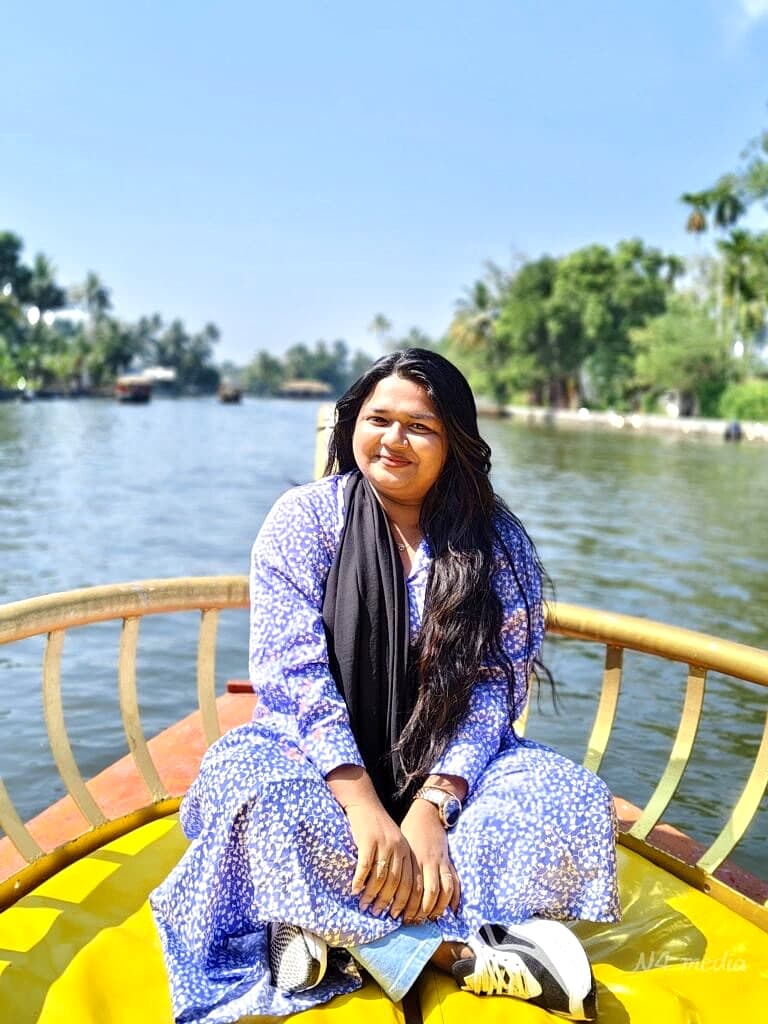 Guest enjoying a peaceful boat ride with lush coconut palm groves and blue skies along Champakulam canals