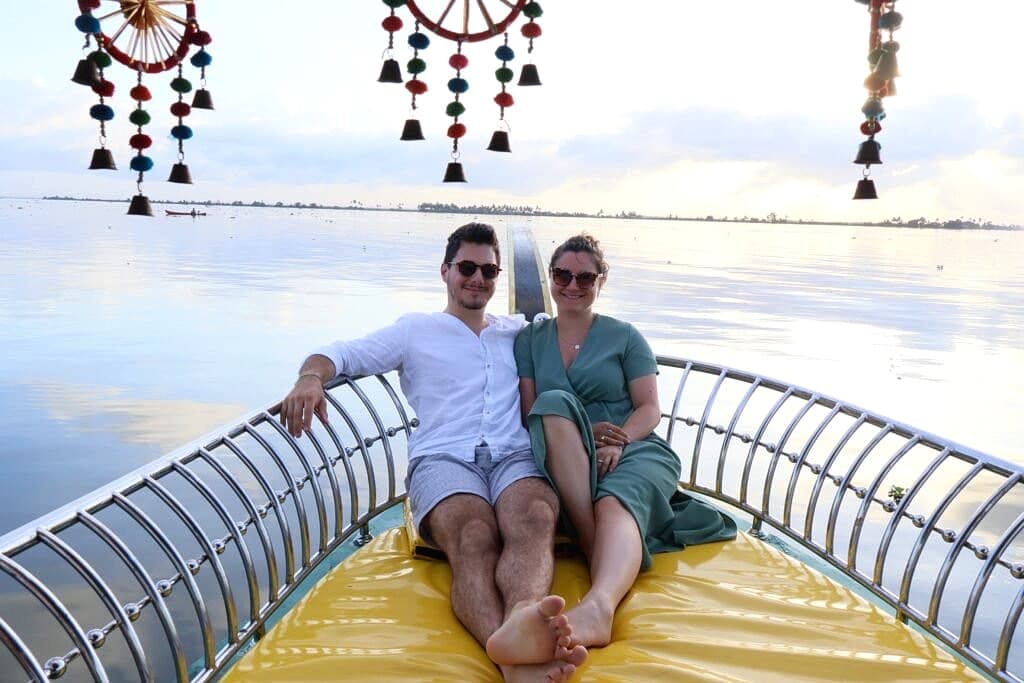 Couple smiling on the shikara boat deck framed by colorful handcrafted hanging dreamcatchers