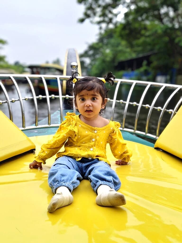 Young child smiling while seated comfortably on the cushioned sun deck of a shikara boat
